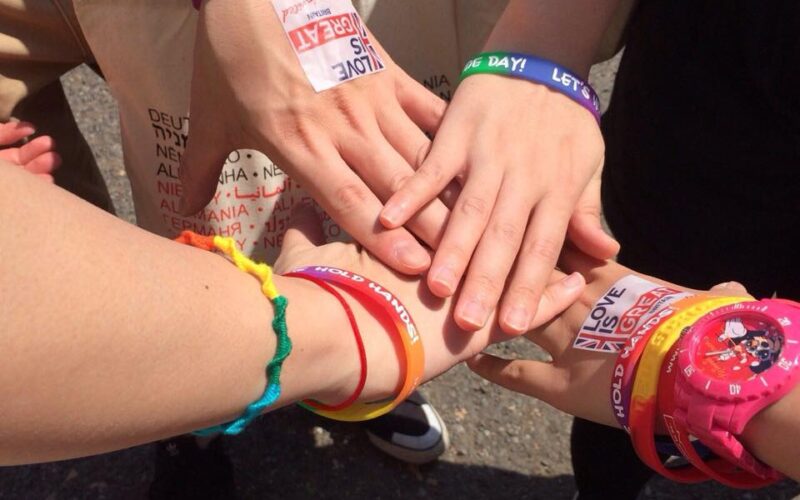 A photo of people wearing colorful rubber bands clasping their hands together