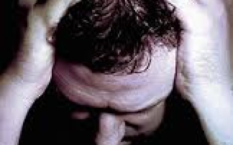 Photo of a man holding his head with both hands
