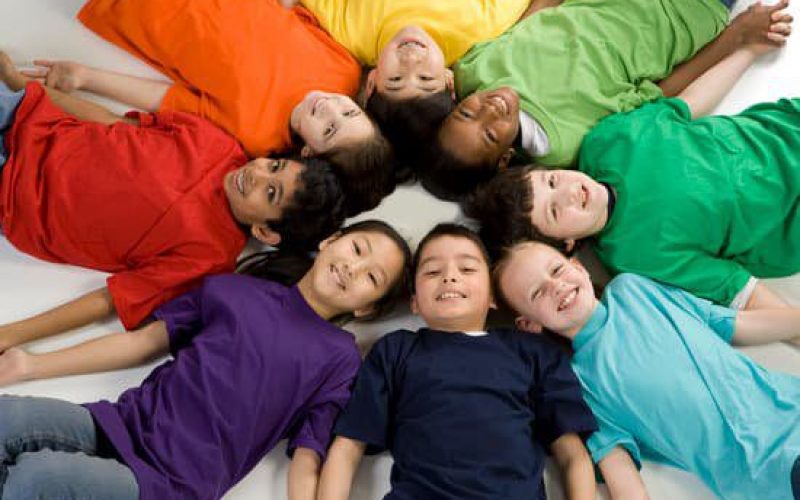 Photo of children wearing colorful T-shirt lying on the ground.