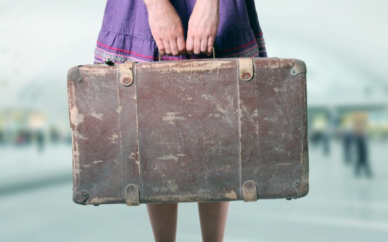 A photo of a woman holding an old trunk in both hands